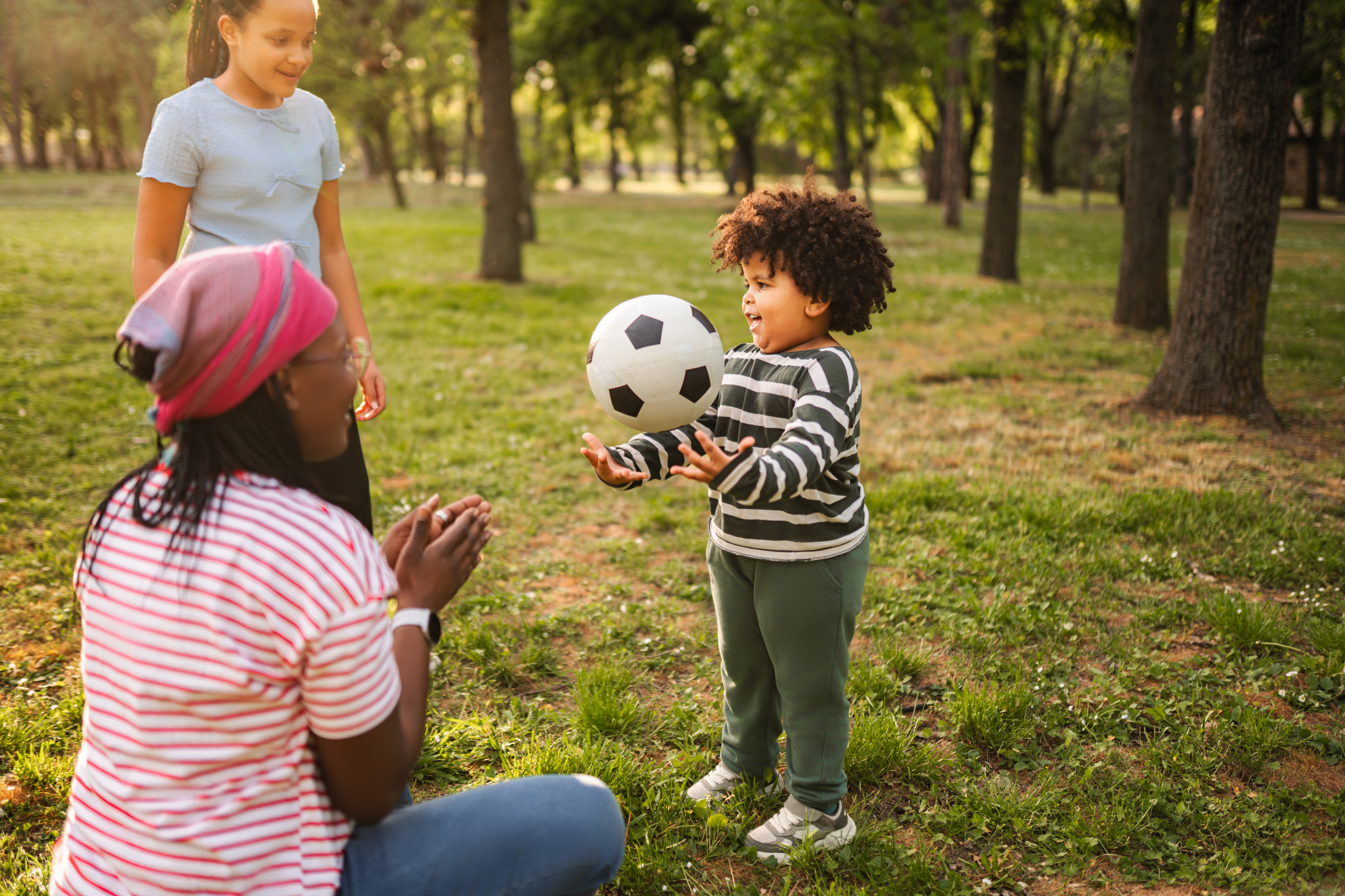 Family enjoying playing soccer in a park on a sunny day